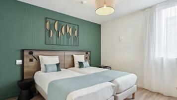 Een moderne slaapkamer met twee bedden, een houten hoofdbord, een kunstwerk aan de muur en een groot raam met gordijnen.