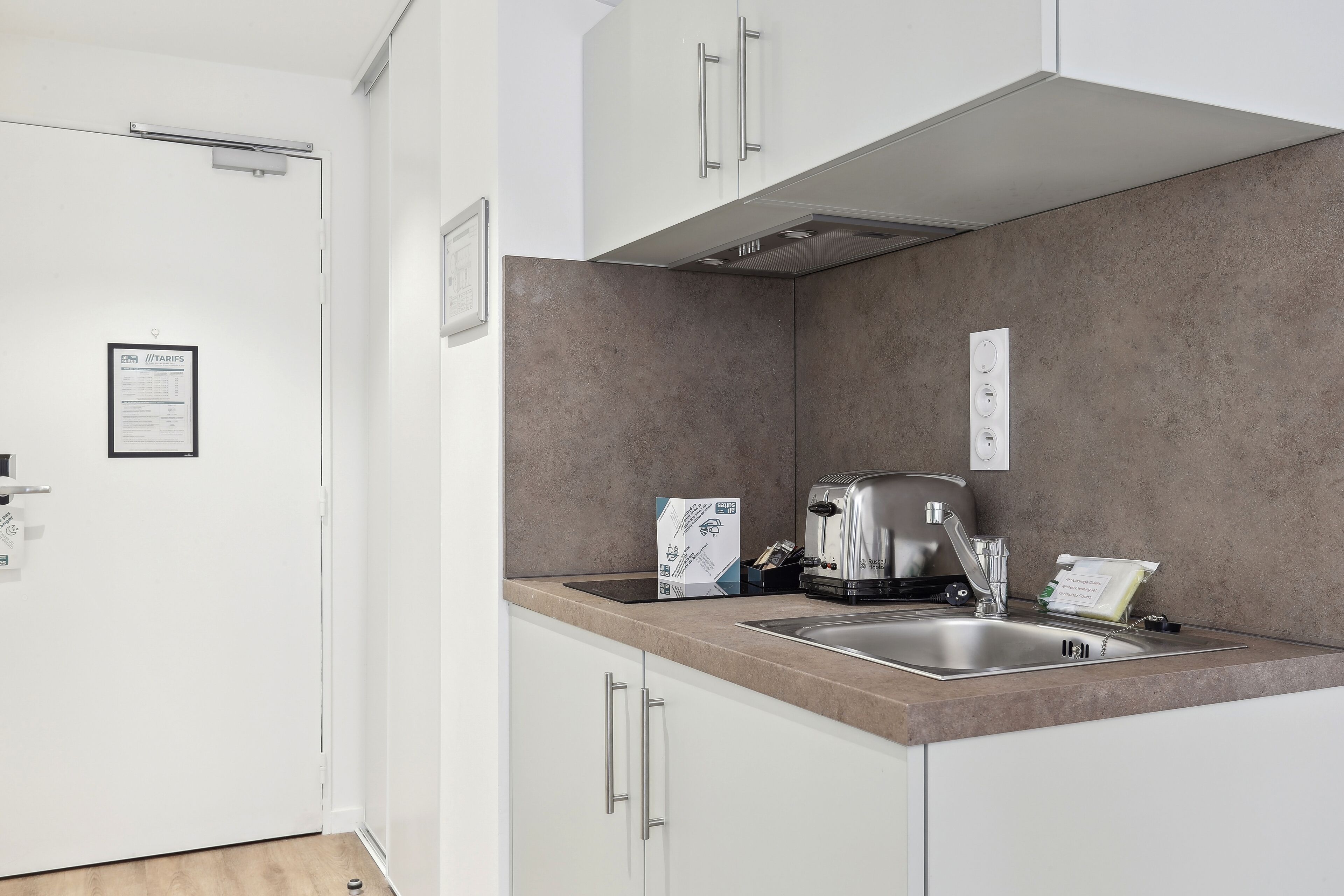 Een moderne keuken met witte kasten, een roestvrijstalen spoelbak en een ingebouwde toaster.