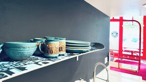 A kitchen shelf with ceramic mugs and bowls.