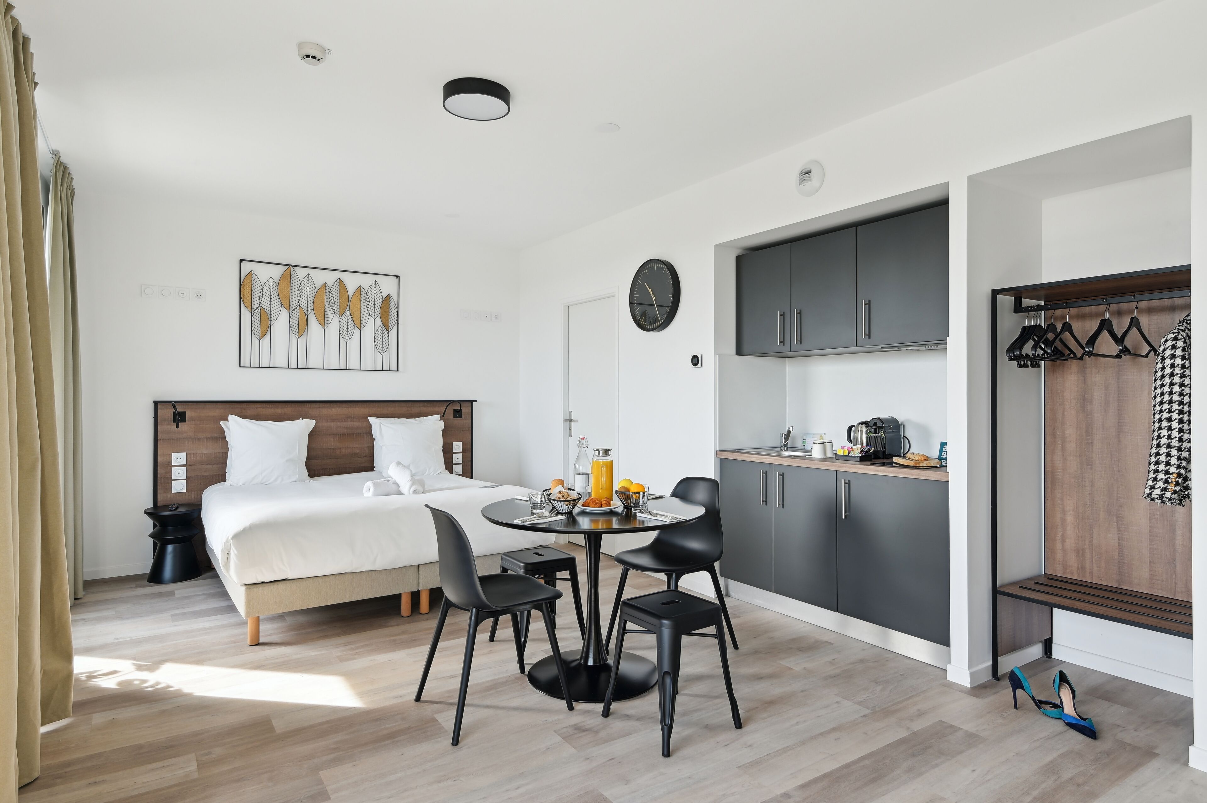 Une chambre d’hôtel moderne équipée d’un lit, d’une table de chevet et d’un coin repas avec des chaises et une table.