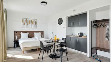 Une chambre d’hôtel moderne équipée d’un lit, d’une table de chevet et d’un coin repas avec des chaises et une table.