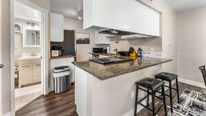 Eine moderne Küche mit Granitarbeitsplatte, Edelstahlgeräten und einer integrierten Kochinsel mit Barhocker.
