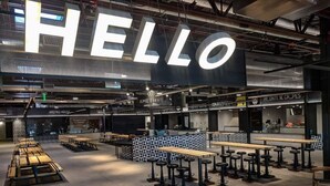 Ein modernes Café-Interieur mit einem großen 'HELLO'-Schild, Sitzbereichen und einer Kaffeetheke.