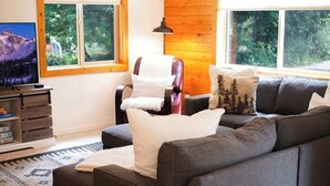 Una sala de estar con un sofá, un sillón y un televisor sobre un mueble de madera.