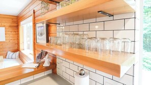 Un interior de madera con una encimera de cocina, estantes y una zona de estar.