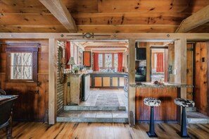 Een rustiek houten interieur met een keuken, houten balken en een stenen open haard.