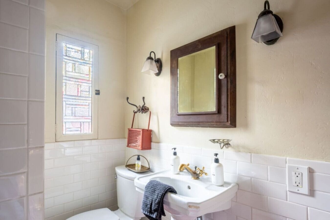 Une salle de bain équipée de toilettes, d’un lavabo et d’une fenêtre donnant sur des immeubles.