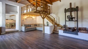 A spacious living area with a loft bedroom, wooden staircase, and a vintage mechanical device on display.