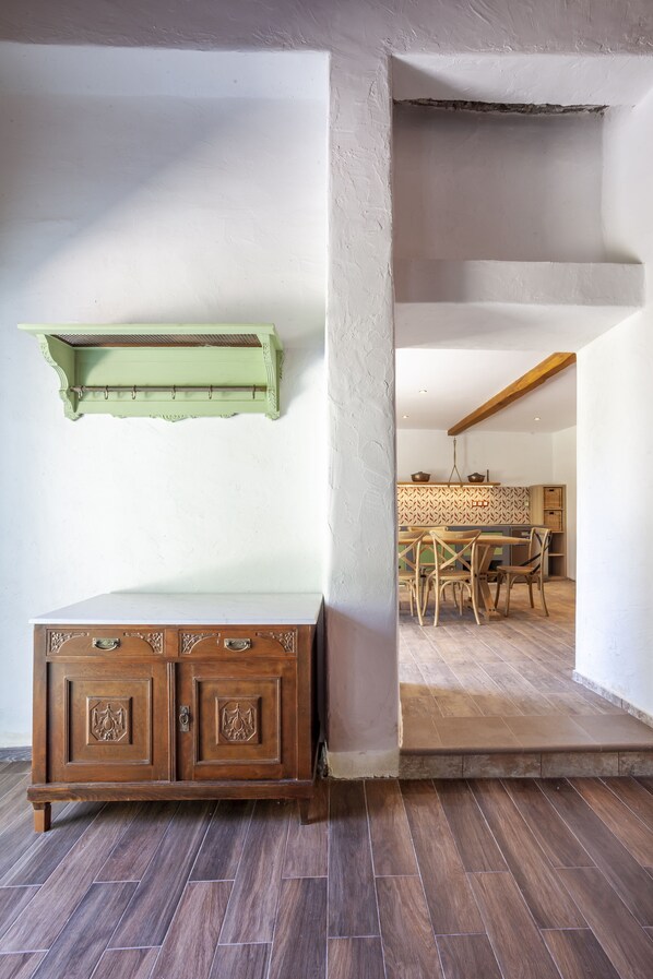 Una habitación con un armario de madera, un estante verde y una zona de comedor con sillas y una mesa.