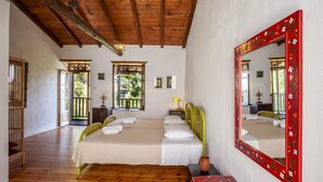 A bedroom with a wooden ceiling, a large mirror with floral design, and a bed with green headboards.