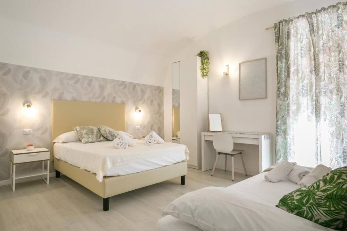 A modern bedroom with a bed, bedside tables, a desk, and a mirror.