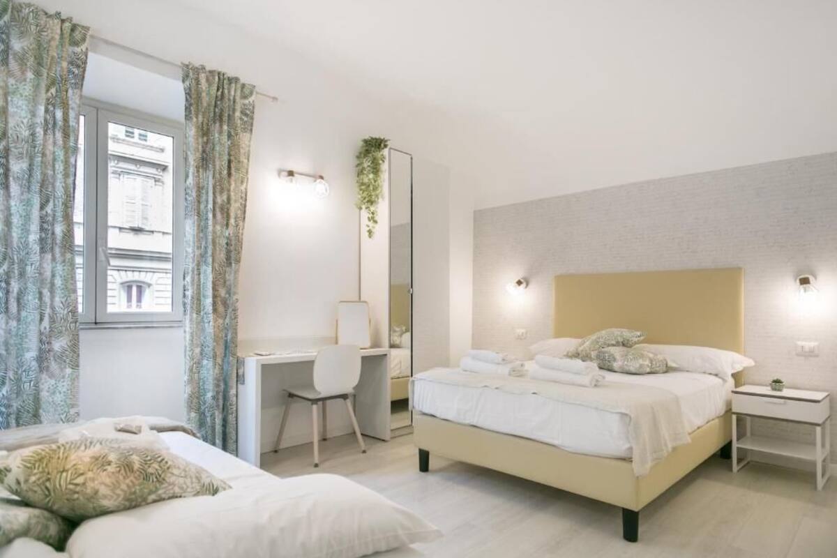 A modern bedroom with a large bed, a desk, and a chair.