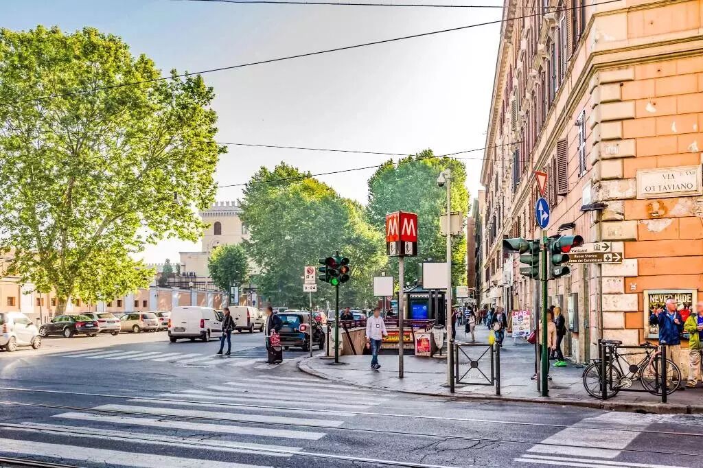 Una intersección de calles con semáforos, un paso de peatones y un edificio con un cartel que dice 'VIA XXI OTAVIANO'.
