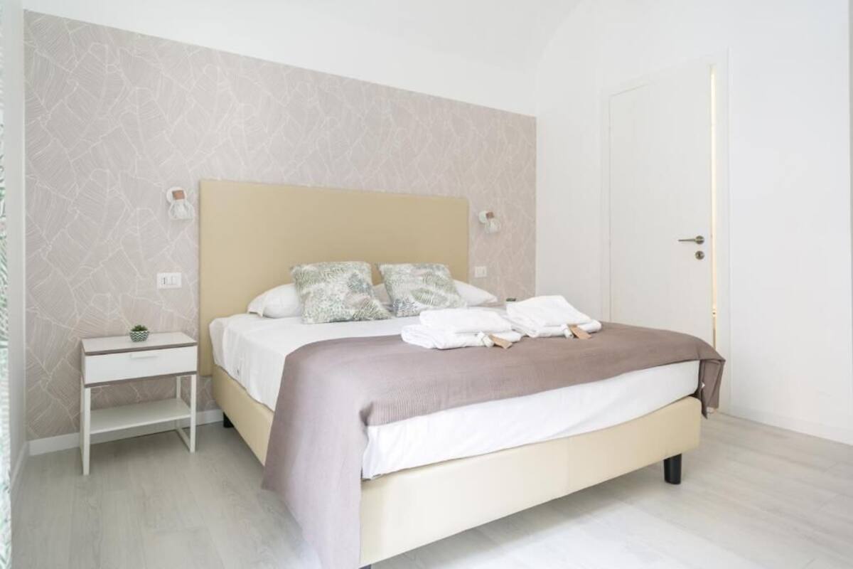 A neatly arranged bedroom with a bed, bedside tables, and a door.