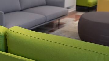Un soggiorno moderno con un divano grigio, una poltrona verde e un pouf scuro.