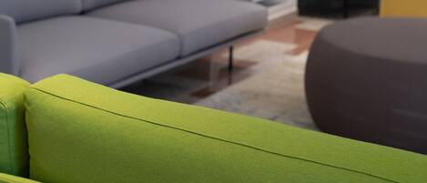 Una sala de estar moderna con un sofá gris, un sillón verde y un otoman oscuro.