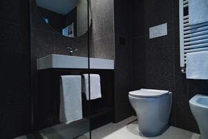 Un baño moderno con ducha envuelta en cristal, un lavabo blanco y un inodoro.