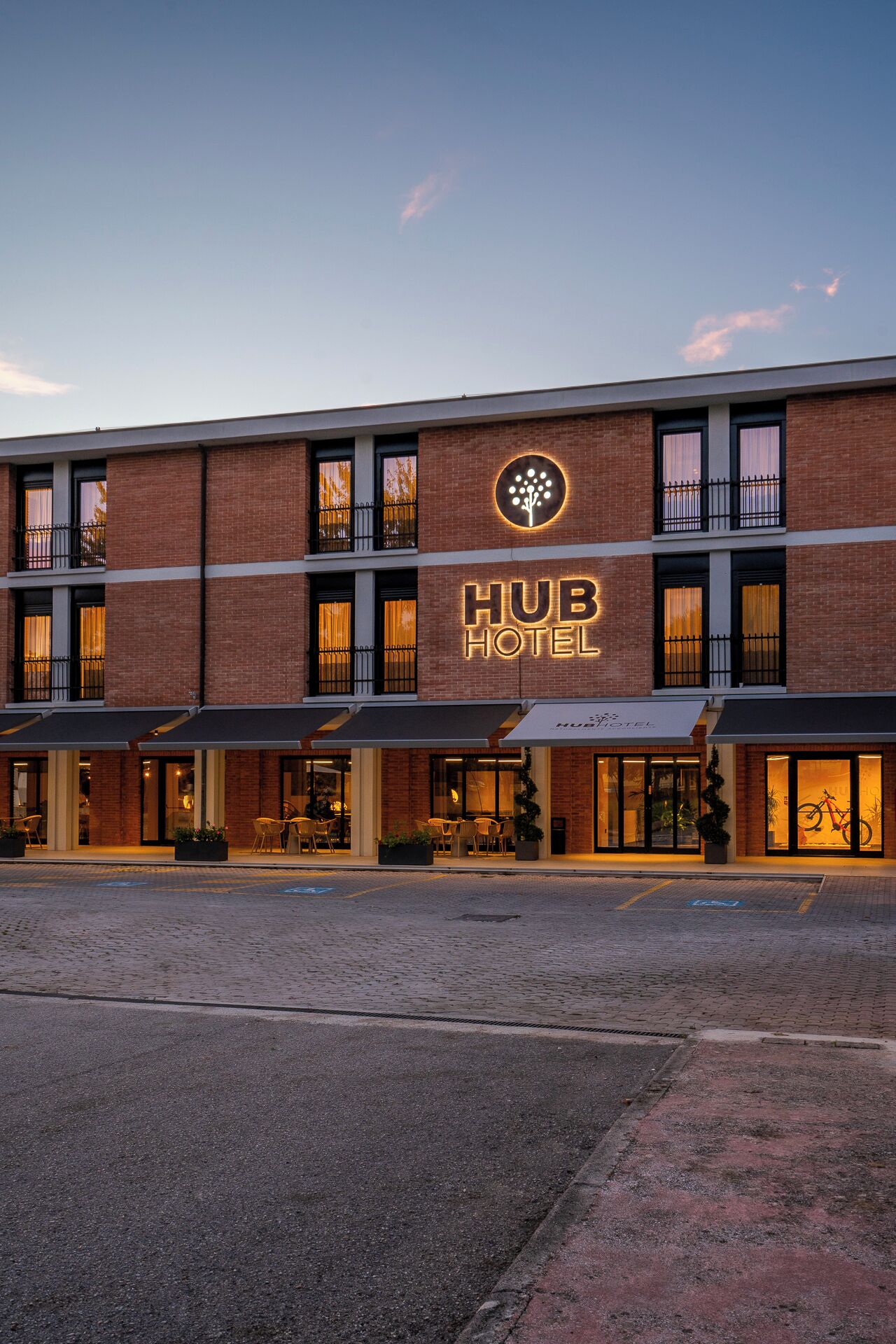 Un Hub Hotel con fachada de ladrillo moderno, amplias ventanas y zona de estar al aire libre.