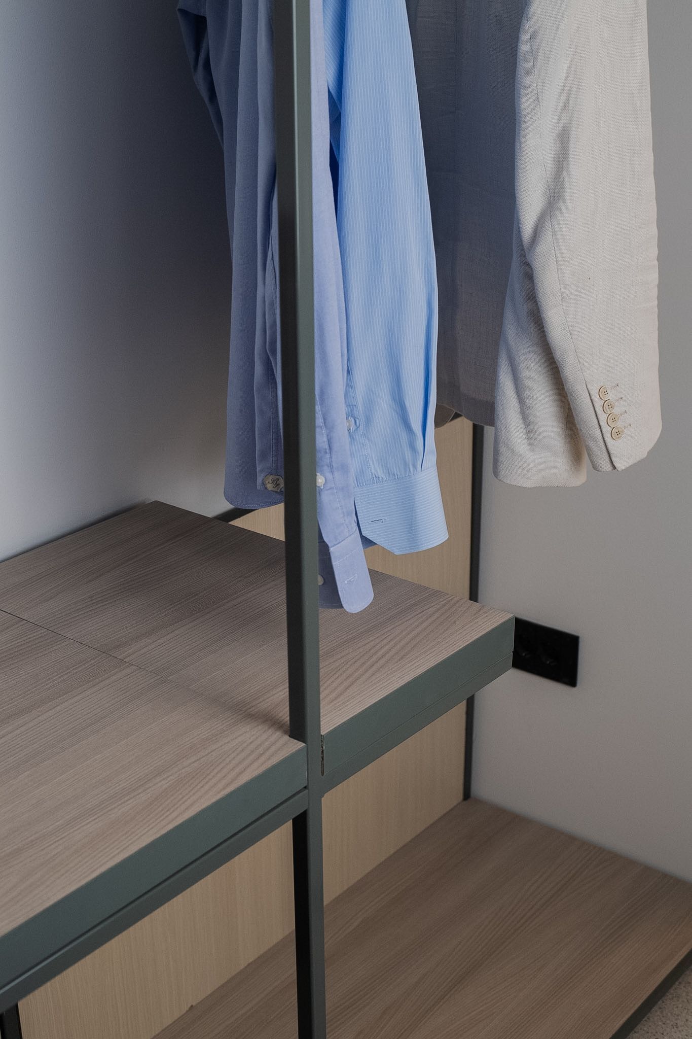 A bunk bed with a wooden platform and metal frame, featuring a hanging towel and a folded shirt.