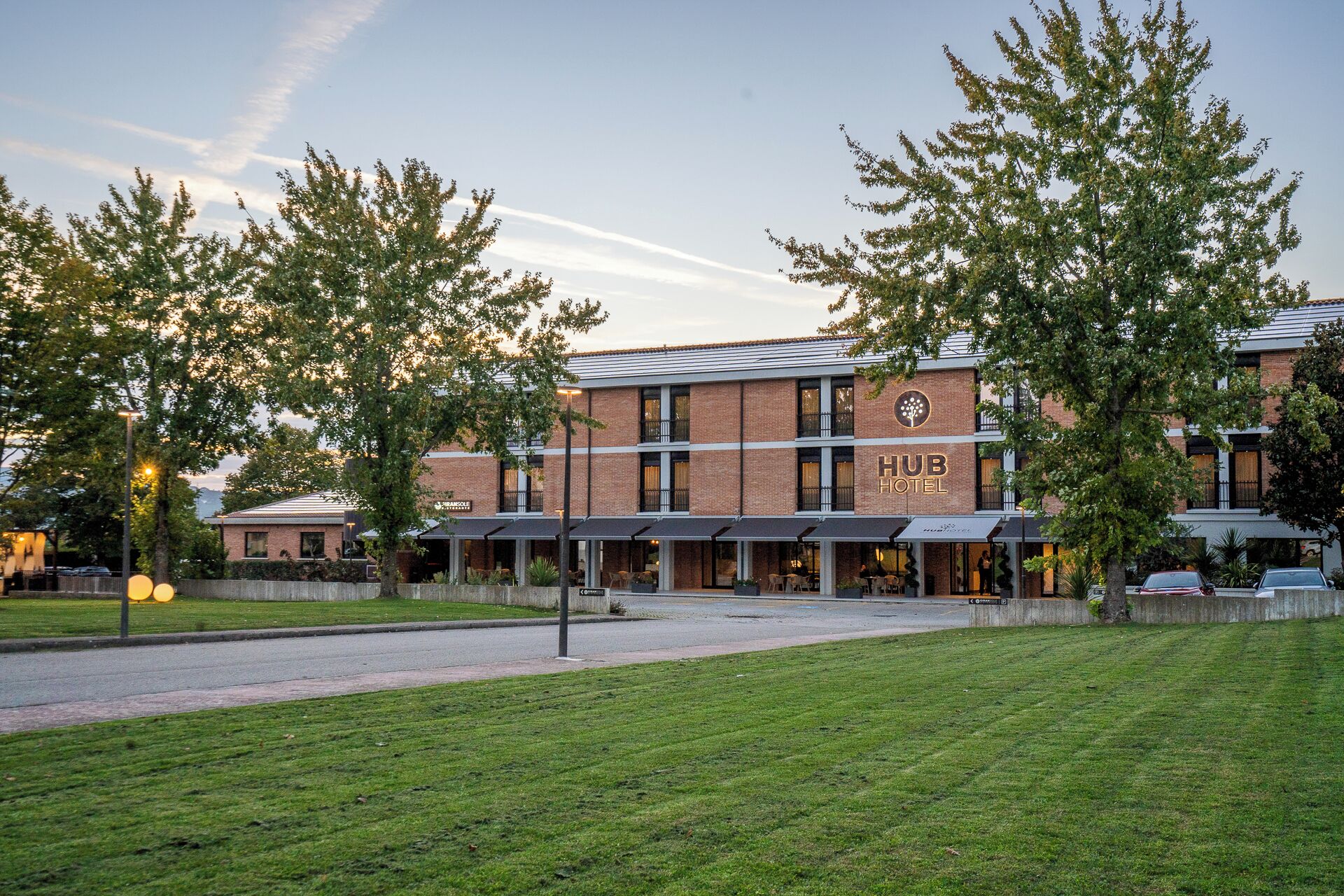 A HUB HOTEL with a brick facade, outdoor seating area, and a well-maintained lawn.