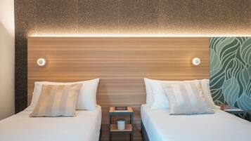 A hotel room with two beds, a nightstand with a lamp, and a wall with a textured pattern.