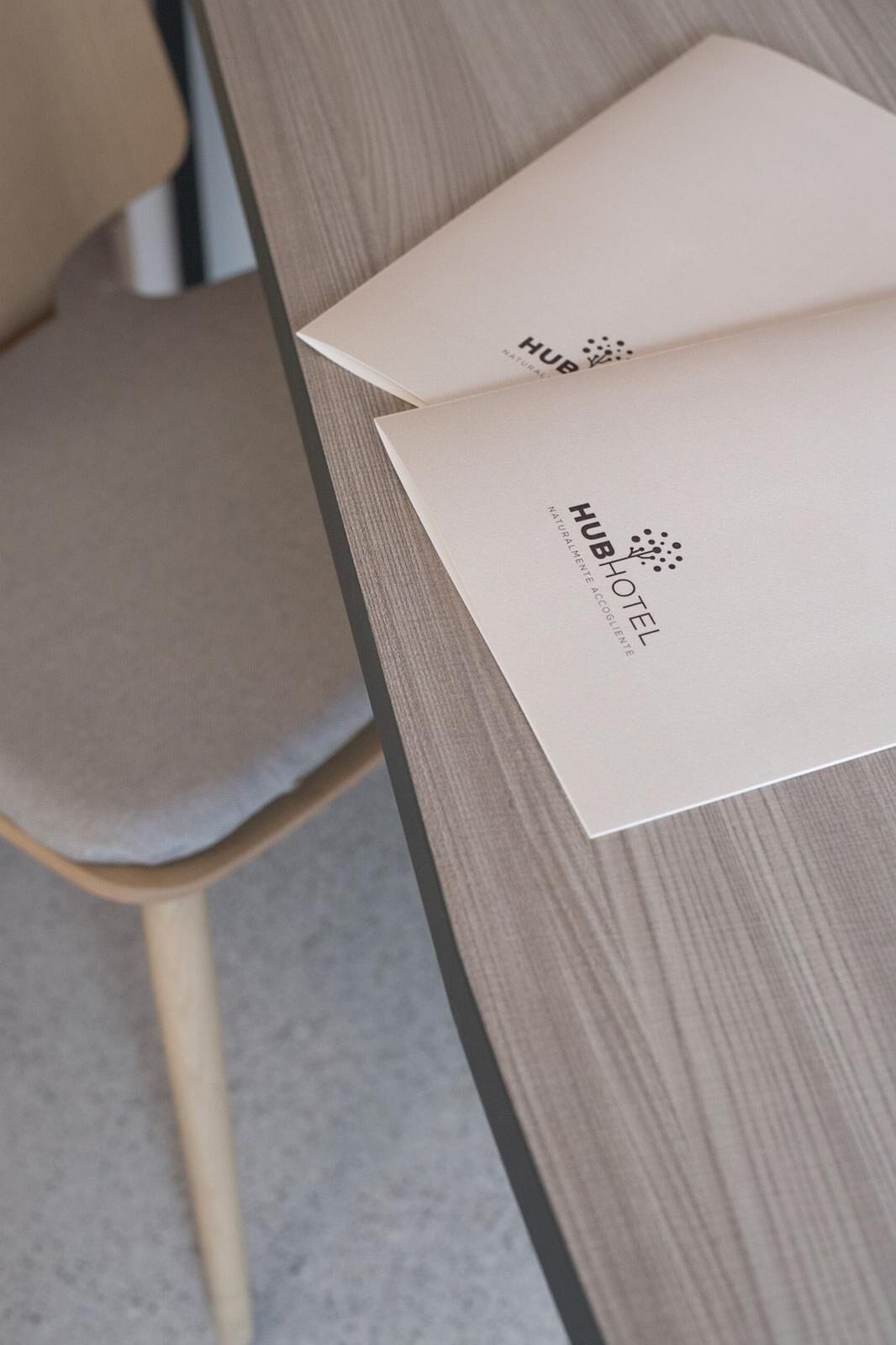 Een houten tafel met twee witte papieren erop, waarvan één de tekst 'HUBHOTEL' en 'NATURALLY ACCELERATED' bevat.