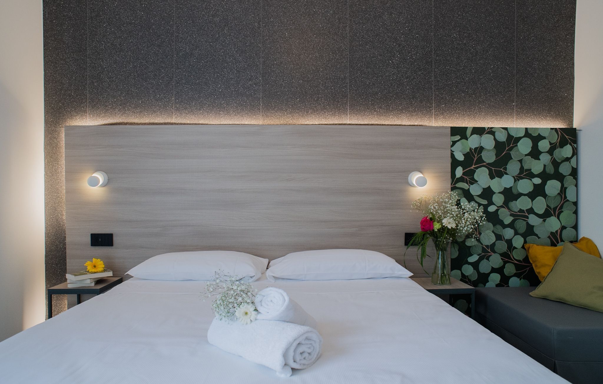 A modern hotel room with a large bed, two bedside tables, and a nightstand.