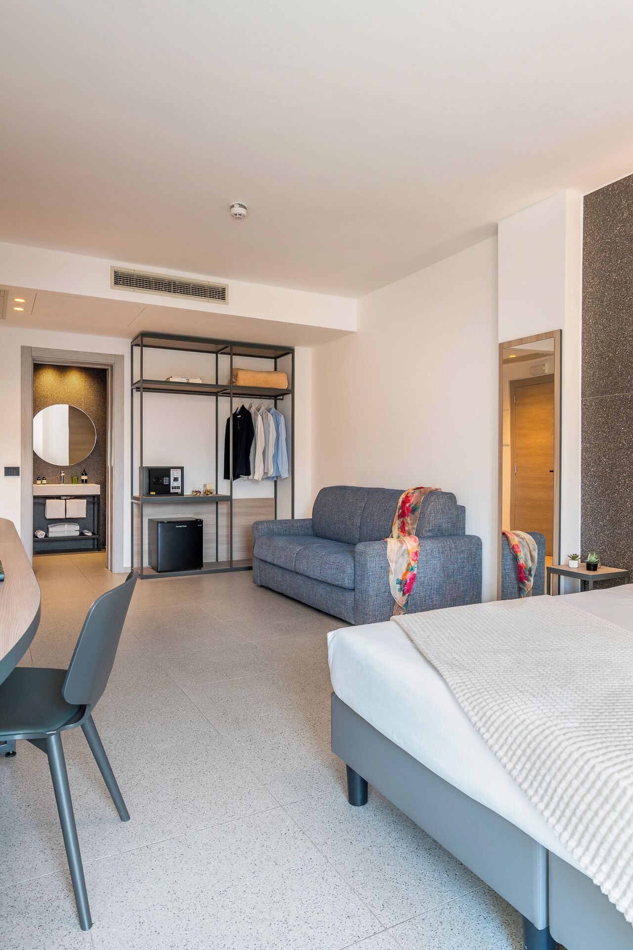 Una habitación de hotel moderna con cama, escritorio, sofá y armario.