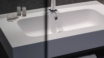 Um banheiro moderno com uma pia branca, uma torneira preta e duas toalhas brancas penduradas em um suporte.