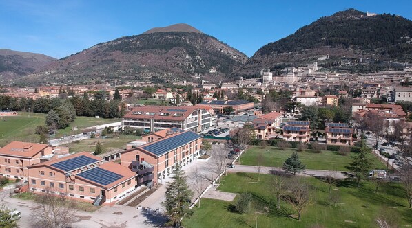 A town with a mix of residential and commercial buildings, including a prominent building with solar panels. - Hub Hotel (Gubbio)