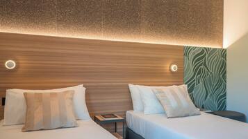 Habitación de hotel con dos camas, cabecero de madera y pared con estampado verde.