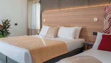 Ein Hotelzimmer mit einem großen Bett, einem kleineren Bett, einem Nachttisch, einer Pflanze und einem modernen Wanddesign.