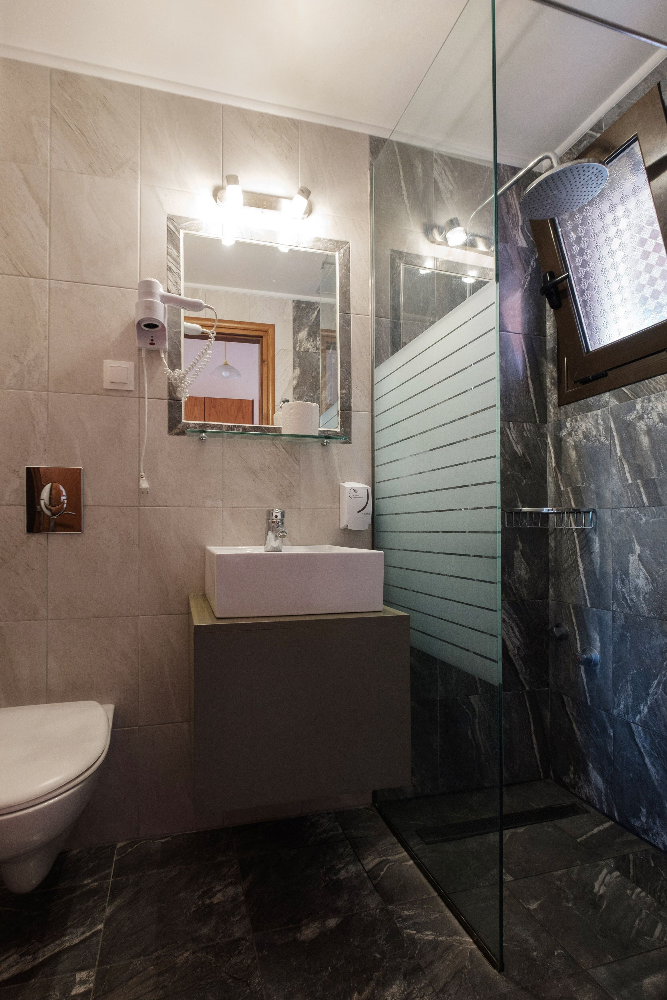 Un baño moderno con cabina de ducha de vidrio, un lavabo blanco y un inodoro.