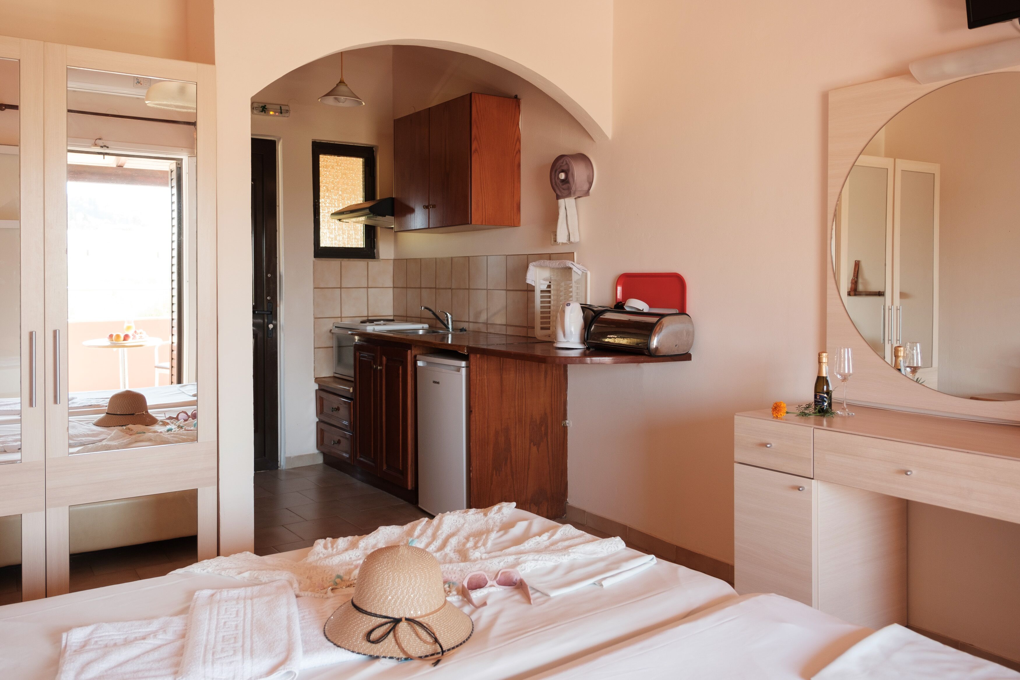 A hotel room with a bed, a bathroom, a kitchen area, and a large mirror.