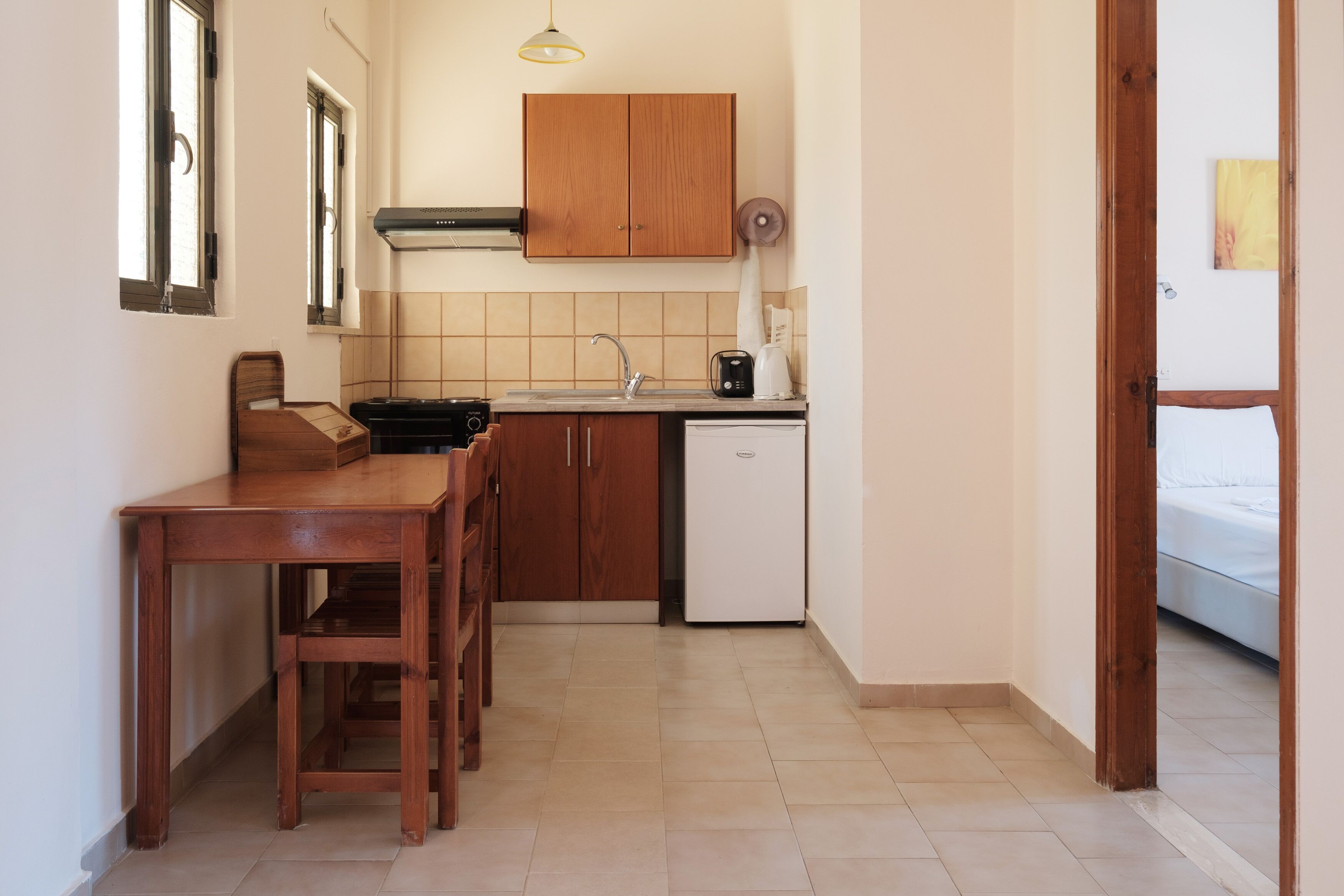 Una cocina compacta con armarios de madera, un lavamanos, una cafetera y un refrigerador.