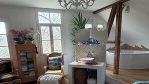 A room with a round rug, a chair, a sofa, a bookshelf, a plant, a chandelier, and a bathtub. - Dreamholiday - Stylish large vacation home with garden for 20+ people (Mittelhof)
