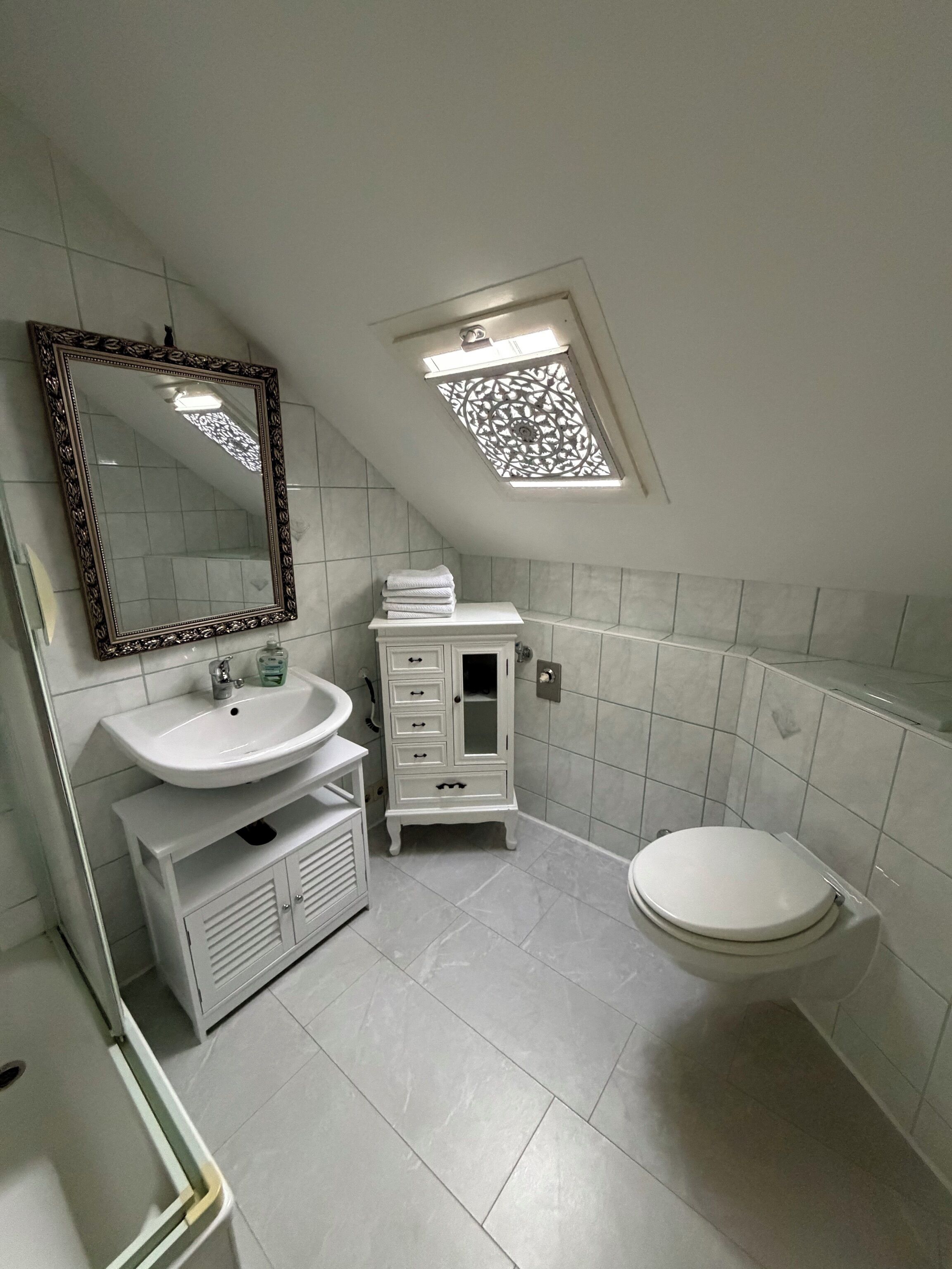 Ein Badezimmer mit weißem Waschbecken, Waschtisch und Toilette.