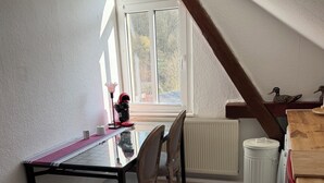 Uma área de refeições com mesa, cadeiras, uma janela e um radiador.
