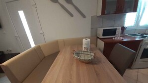 Eine Küche mit Holztisch, beiger Couch und Mikrowelle.