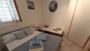 Ein ordentlich eingerichtetes Schlafzimmer mit einem Bett, einem Nachttisch, einer Uhr und einem Fenster mit Jalousien.