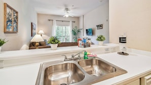 A modern kitchen with a double sink, a ceiling fan, and a window with curtains. - 3BR Condo at Bahama Bay Resort (Davenport)