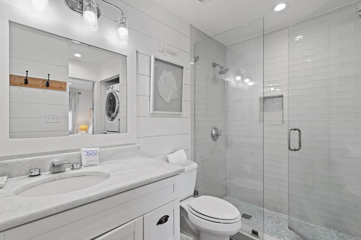 Une salle de bain moderne avec un grand miroir, un lavabo, des toilettes et une douche à parois de verre.