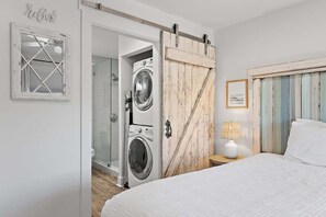 A bedroom with a bed, a nightstand, a lamp, a wardrobe, and a washing machine. - Seagrove - Commodore Retreat 202 (Santa Rosa Beach)