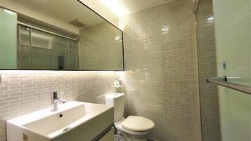 A bathroom with a white sink, toilet, and glass shower enclosure.