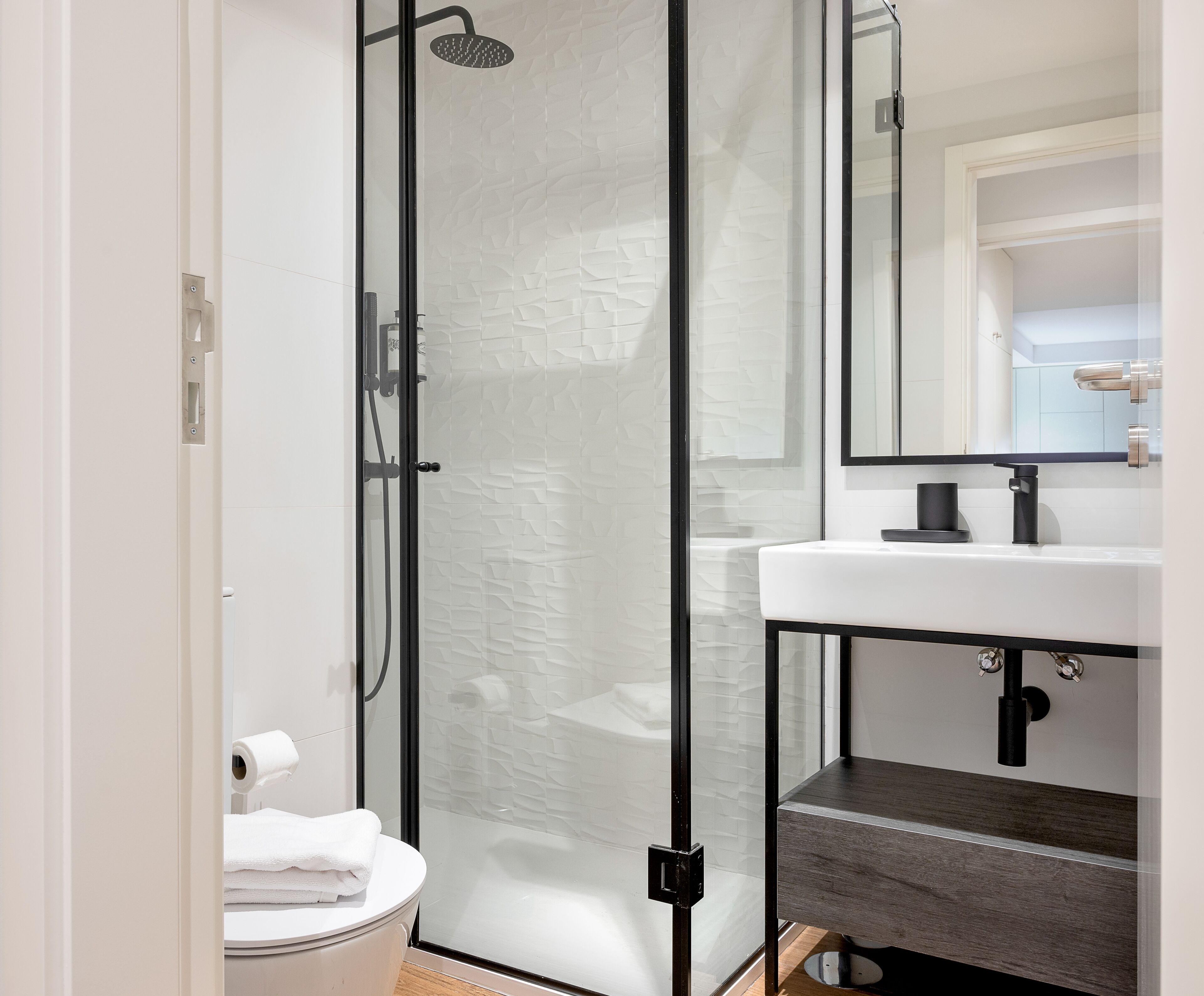 A modern bathroom with a glass-enclosed shower, a white sink, and a mirror above the sink.