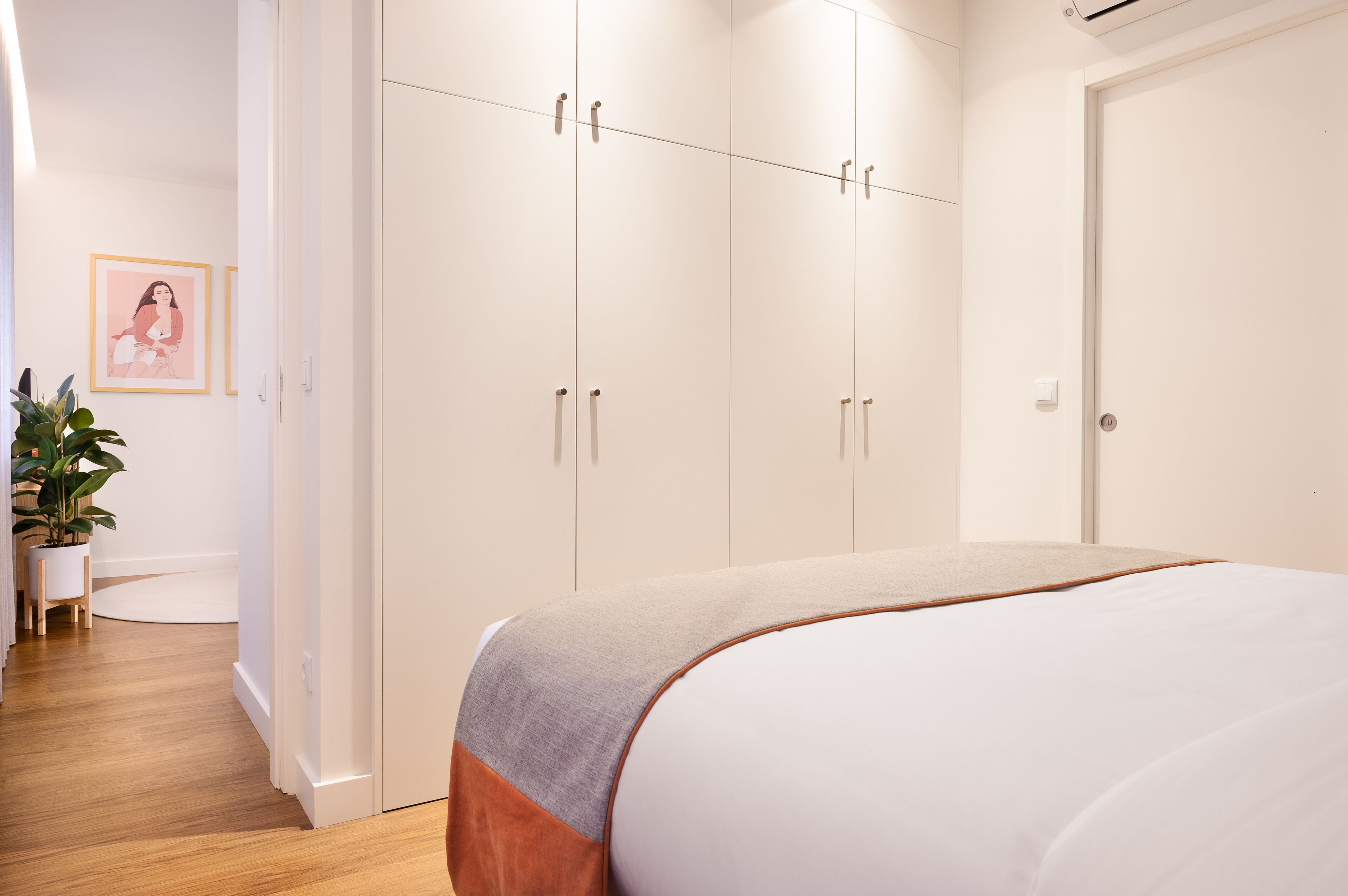 Une chambre à coucher avec un grand lit, une armoire blanche et une plante en pot.