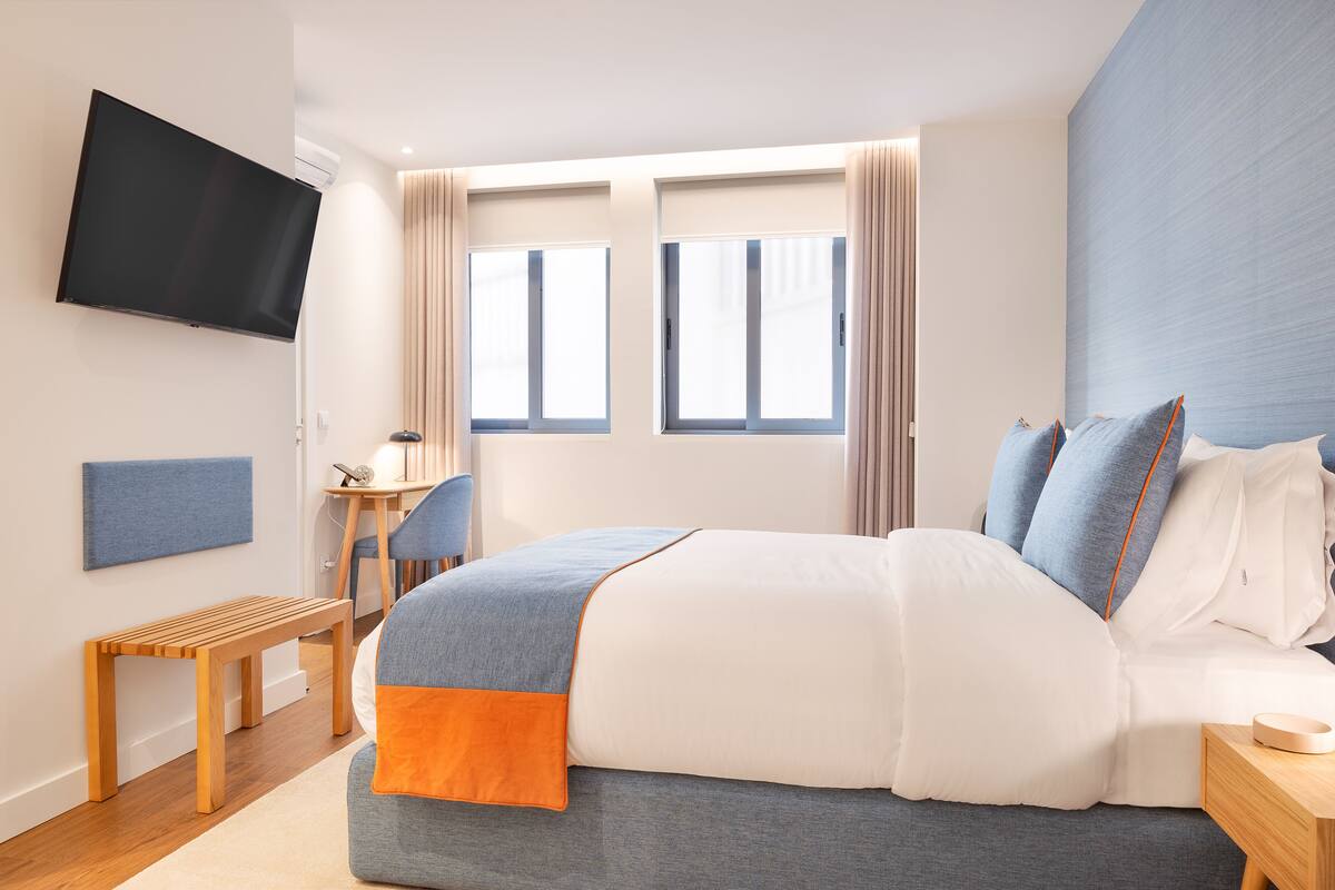 Een moderne hotelkamer met een groot bed, een bureau en een flatscreen televisie aan de muur.