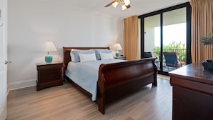 A bedroom with a wooden bed, two bedside tables with lamps, a ceiling fan, and a view of the outdoors through a sliding glass door. - Stay 2 nights and get an extra night free! - Unit 116 - Exceptions Apply (Dauphin Island)
