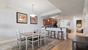 A modern kitchen with white cabinets, a central island, and a dining area with a wooden table and white chairs. - Stay 2 nights and get an extra night free! - Unit 116 - Exceptions Apply (Dauphin Island)