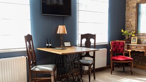 A dining area with a wooden table, chairs, a lamp, and a television mounted on the wall. - Vintage Apartments BLACK / Free parking (Riga)
